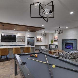 A modern game room featuring a pool table, television, and stylish seating area with decorative lighting.