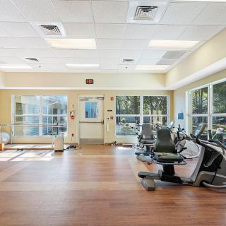 A brightly lit gym with exercise equipment and spin bikes.