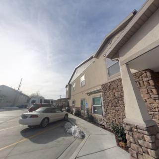 A residential building with parked cars in a parking lot on a sunny day.