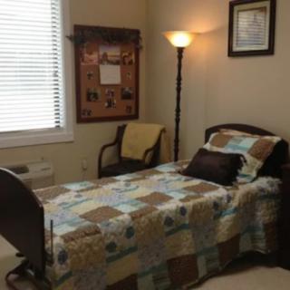 A small bedroom with a single bed, floor lamp, and wall decorations.