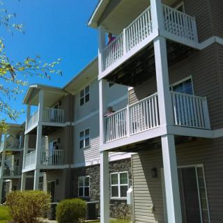 A modern apartment building with multiple balconies under a clear blue sky.