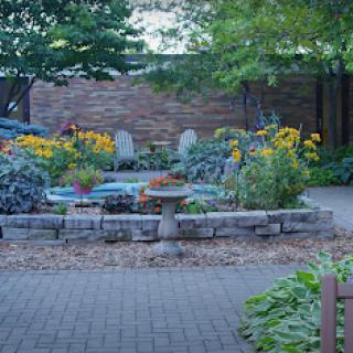 A serene garden filled with colorful flowers and a central birdbath, surrounded by greenery.