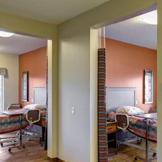 A view of two adjacent hospital rooms with beds and medical equipment.