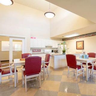 A bright, spacious dining area with red chairs and a kitchen in the background.