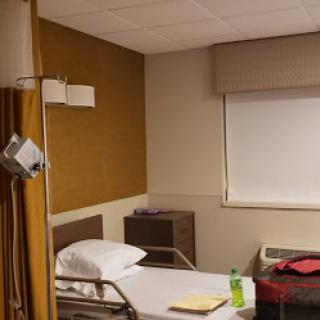 A view of a hospital patient room featuring a bed and basic furnishings.