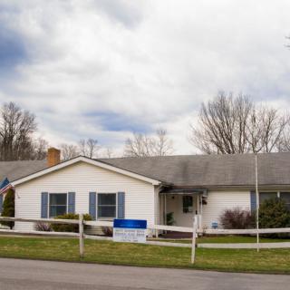 A suburban house with a fenced yard under a cloudy sky.