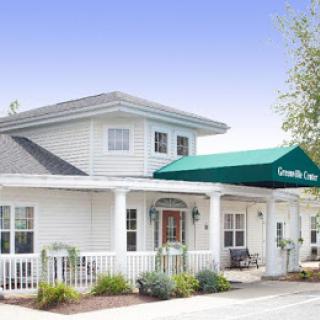 A two-story white building with a green awning over the entrance.