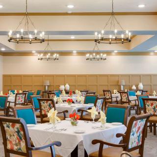 An elegant dining room with neatly arranged tables and chairs, adorned with chandeliers.