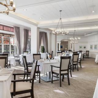 An elegant restaurant interior featuring neatly arranged tables and chairs, with chandeliers providing a warm ambiance.