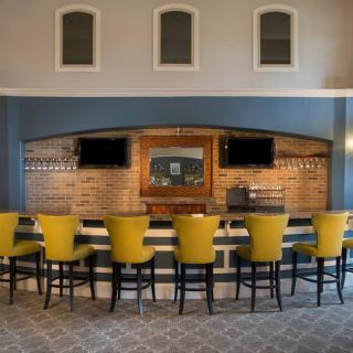 A modern bar interior featuring a row of yellow chairs and television screens.