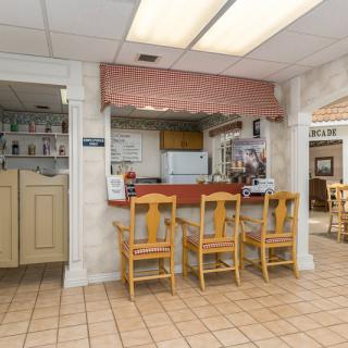 A cozy restaurant interior featuring a counter with wooden chairs and a view into the kitchen area.