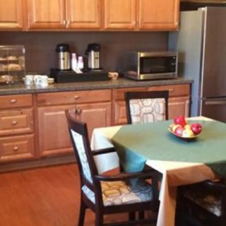 A cozy kitchen and dining area with wooden cabinets, a table with chairs, and various appliances.