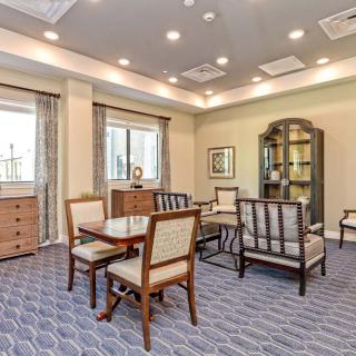 A well-furnished living area with chairs, a table, and a bookshelf under warm lighting.