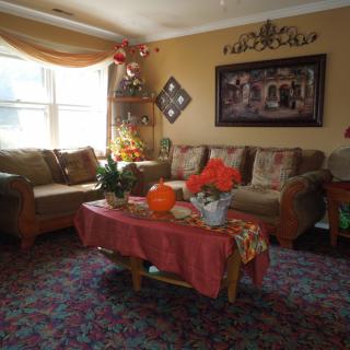 A cozy living room with a large sofa, coffee table adorned with plants and decorations, and wall art enhancing the decor.