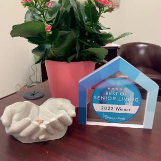 A display of recognition with an award for 'Best Senior Living' alongside a vibrant plant in an office setting.