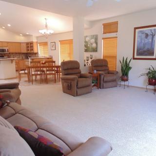 An open-concept living room with comfortable recliners, a cozy sofa, and a view of the kitchen and dining area.