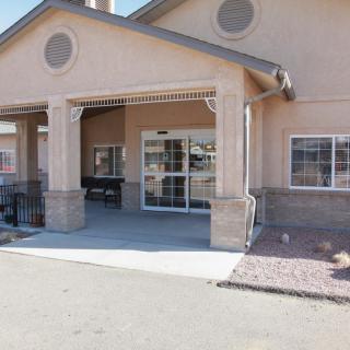 A building with a covered entrance and a sidewalk leading to the door.