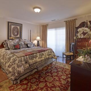 A traditionally decorated bedroom with a large bed, patterned rug, and elegant curtains.