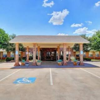 Entrance to a building with columns and a parking lot under a clear blue sky.