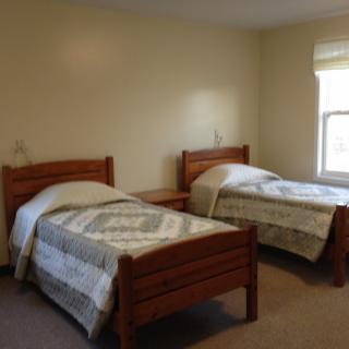 A simple bedroom with two twin beds and a window.