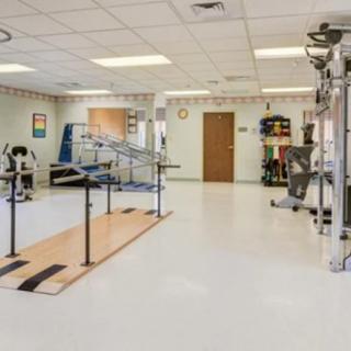 A spacious physical therapy room equipped with rehabilitation tools and parallel bars.