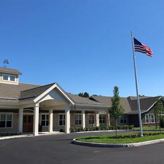 An exterior view of a building with an American flag in front, set against a clear blue sky.