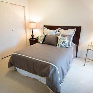 A cozy bedroom with a neatly made bed, flanked by a lamp and nightstand.