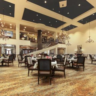 A spacious and elegantly designed restaurant dining area with chandeliers and neatly arranged tables and chairs.