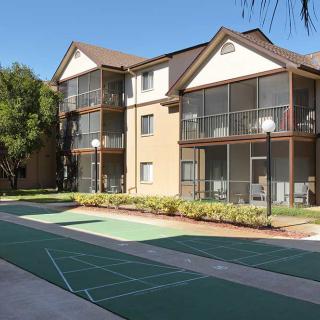 A residential apartment building with outdoor courts and clear skies.