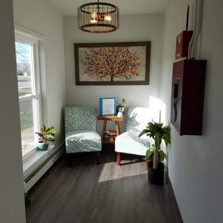 A cozy waiting area with two chairs, plants, and wall art.