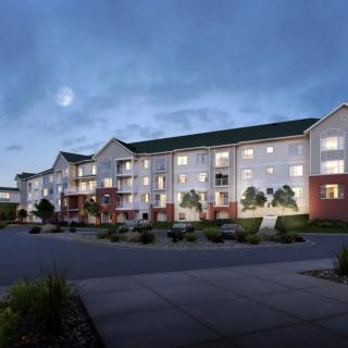A well-lit apartment complex at dusk with a spacious parking area.