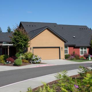 A suburban house with a manicured lawn and driveway leading to a garage.