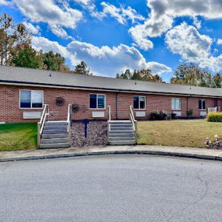 A well-maintained residential building with attractive landscaping and a beautiful cloudy sky.