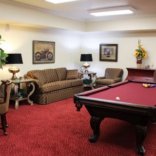 A cozy game room featuring a pool table and comfortable seating with a warm red carpet.