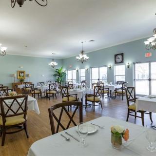 A well-lit dining room with elegantly set tables and chairs, featuring stylish decor and ambient lighting.