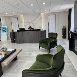A modern lobby with green chairs and a stylish reception desk.