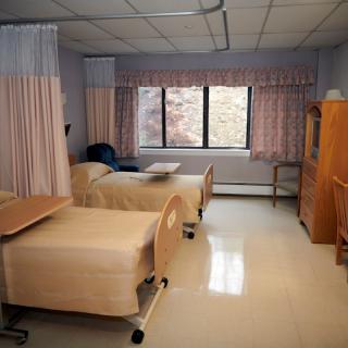 A hospital room with two beds and a large window.