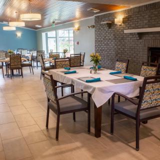 A well-decorated dining area with neatly arranged tables and chairs, featuring elegant lighting fixtures.