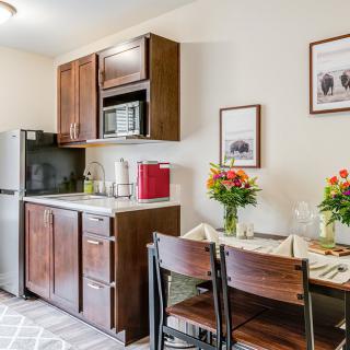A cozy kitchen and dining area with modern appliances and a set table adorned with flowers.