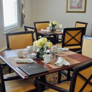 An elegantly set dining table with coffee cups and flowers in a restaurant setting.