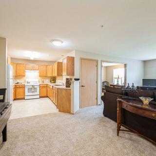 An open-layout living room and kitchen area with wooden cabinetry and comfortable furnishings.