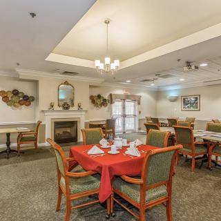 A well-decorated dining room with neatly arranged tables and a cozy fireplace.