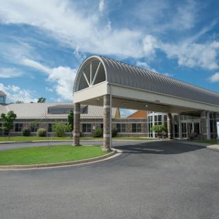 A modern hospital entrance under a clear blue sky.