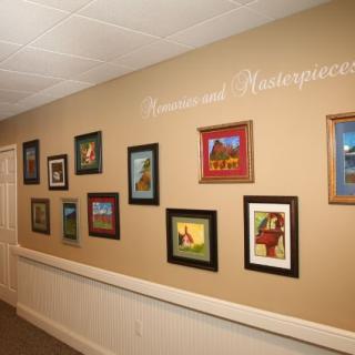 A hallway adorned with a collection of framed paintings, showcasing various colorful artworks.