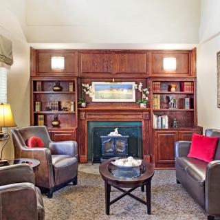 A cozy living room with leather armchairs, built-in bookshelves, and a central fireplace.