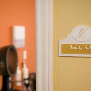 A beauty salon door sign with salon equipment visible in the background.