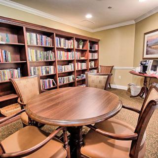 A cozy library room with bookshelves and a wooden table surrounded by chairs.
