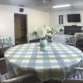A cozy dining area with round tables covered in checkered tablecloths and decorated with floral centerpieces.