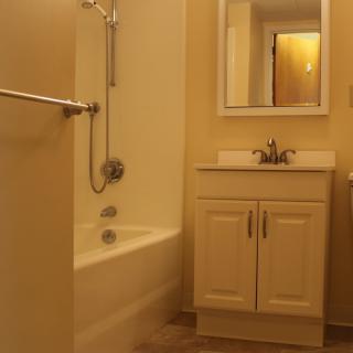 A small bathroom with a bathtub, sink, and mirror.