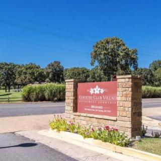 Entrance sign to a scenic area with trees and landscaping.